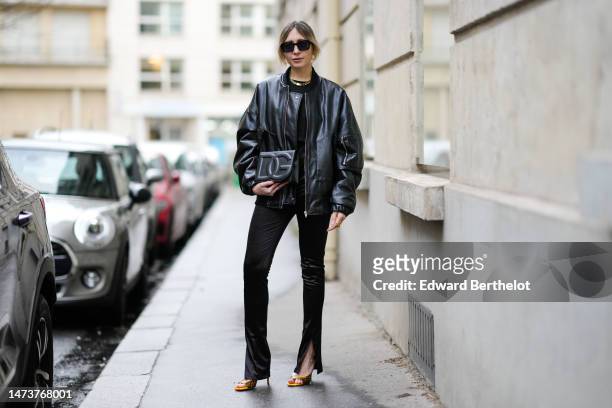 Emy Venturini wears black vintage sunglasses from Woodoo, a golden necklace from Merbabe Greece, a black leather clutch / bag from DG Dolce &...