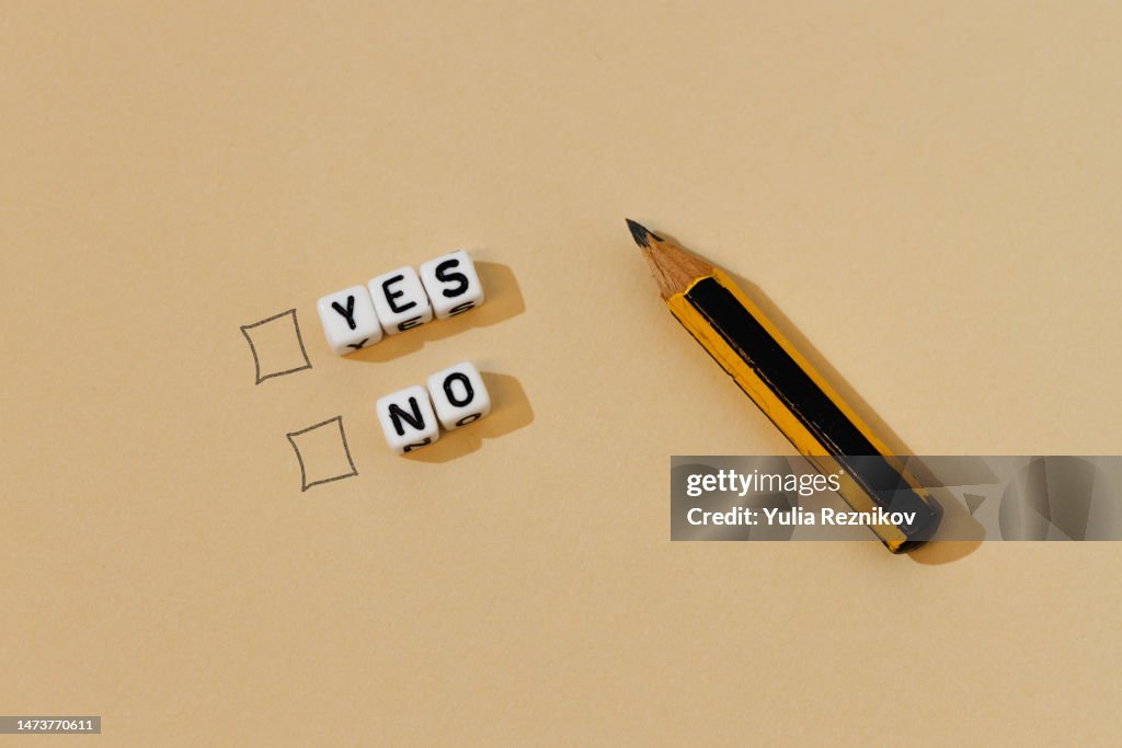 Words yes, no and pencil on the beige background- choice concept