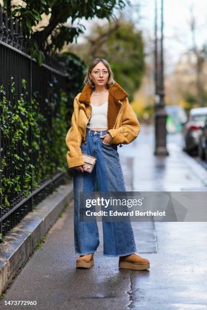 Emy Venturini wears glasses from Ray-Ban, a necklace from CDG Comme des Gar�çons, a beige and brown sheep wool inner lining aviator jacket, a white...