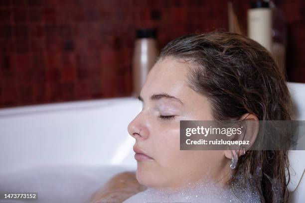 young woman portrait enjoying a bubble bath - woman bath tub wet hair stock pictures, royalty-free photos & images