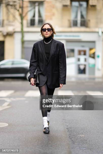 Emy Venturini wears vintage sunglasses from Woodoo, a necklace, a black oversize blazer vintage jacket from Prada, a black turtleneck top / pullover...