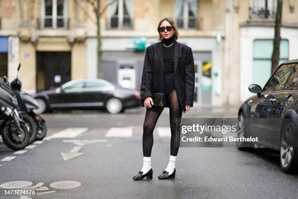 Emy Venturini wears vintage sunglasses from Woodoo, a necklace, a black oversize blazer vintage jacket from Prada, a black turtleneck top / pullover...