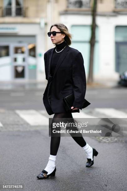 Emy Venturini wears vintage sunglasses from Woodoo, a necklace, a black oversize blazer vintage jacket from Prada, a black turtleneck top / pullover...