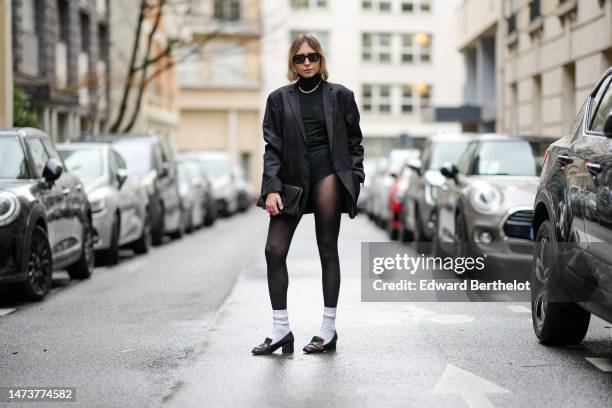 Emy Venturini wears vintage sunglasses from Woodoo, a necklace, a black oversize blazer vintage jacket from Prada, a black turtleneck top / pullover...