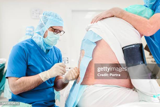 anesthesiologist giving anesthesia into the back a patient before the surgery - cateter imagens e fotografias de stock