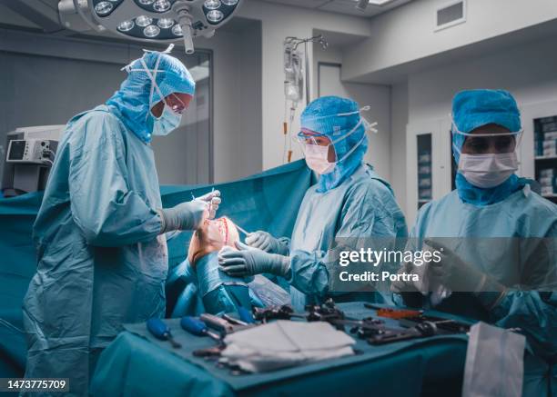 surgeons and nurses performing a knee surgery on patient in operation room - anterior cruciate ligament stock pictures, royalty-free photos & images