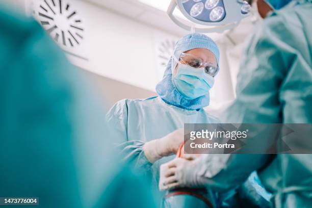 team chirurgico nel bel mezzo dell'operazione di sostituzione del ginocchio - knee replacement surgery foto e immagini stock