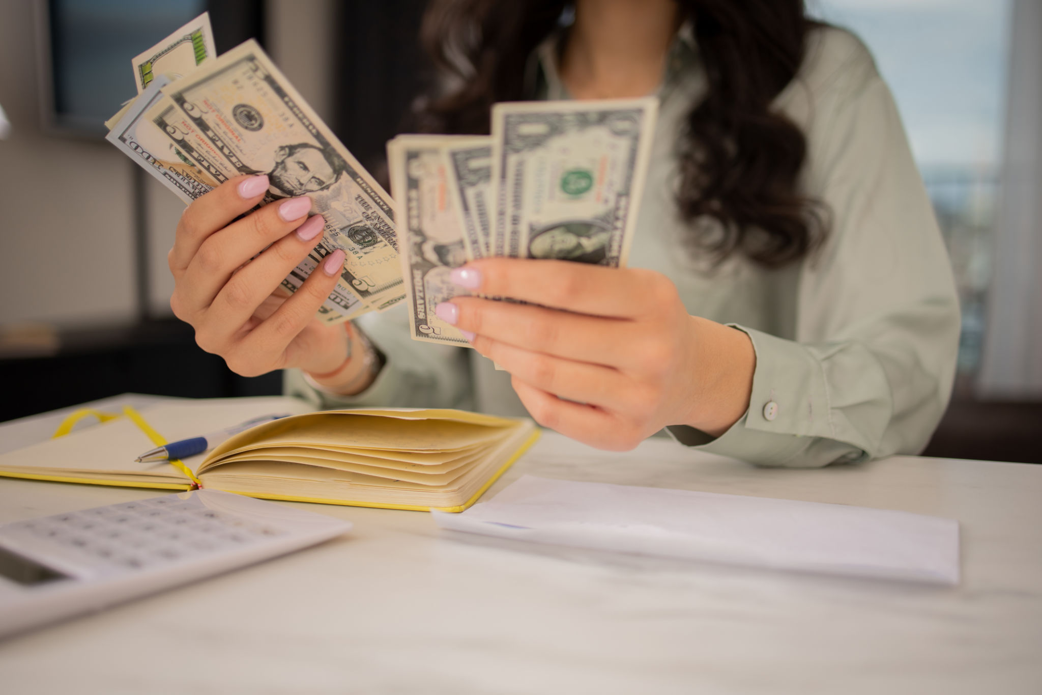 Young woman using calculator while going through bills and home finances Young woman using calculator while going through bills and home finances