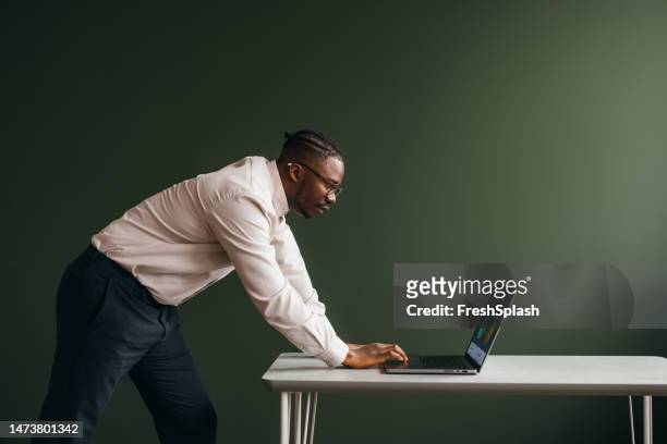 a pensive businessman with glasses working on his computer in the office - desk with green space view stock pictures, royalty-free photos & images
