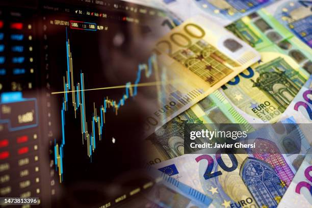 screen with stock market indicators and cash euro banknotes - cambio valuta foto e immagini stock