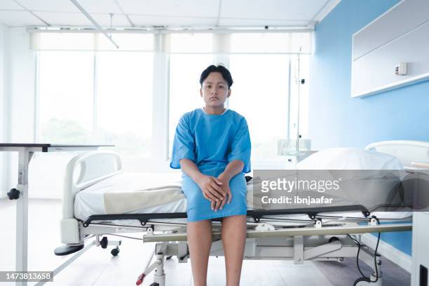 anxious, sad boy wearing hospital gown - hospital gown imagens e fotografias de stock