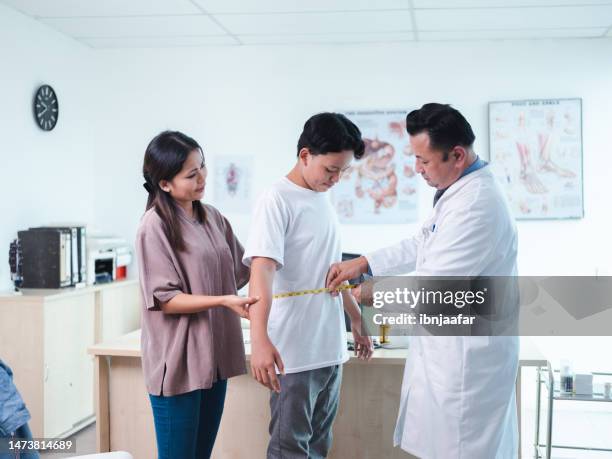 doctor measuring waist of patient with tape - fat asian boy stock pictures, royalty-free photos & images