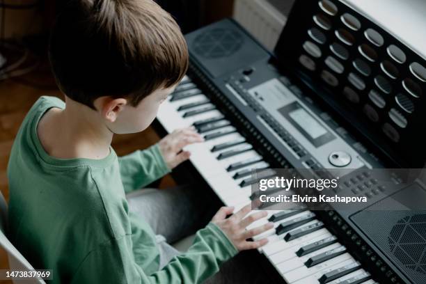 a teenager boy plays the piano at home. musical hobby of a teenager. - synthesizer stock-fotos und bilder