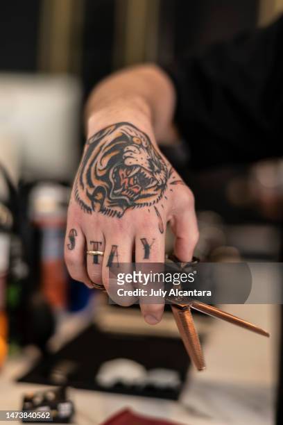 the tattooed hand of a barber with a tiger holds scissors, stay word - alcantara spain bildbanksfoton och bilder