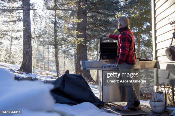 成熟した男性は冬の設定で屋外バーベキューを使用します - bbq winter ストックフォトと画像