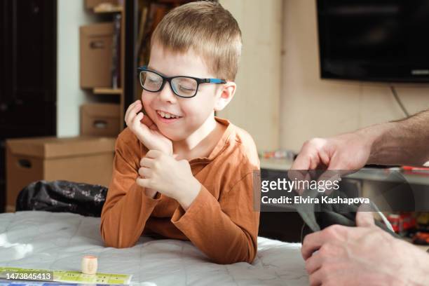 portrait of a smiling boy 8 years old in glasses with a lotto bag in his hands. child playing loto board game - 8 years stock-fotos und bilder