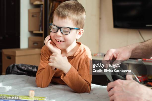 portrait of a smiling boy 8 years old in glasses with a lotto bag in his hands. child playing loto board game - 8 9 years fotos stockfoto's en -beelden