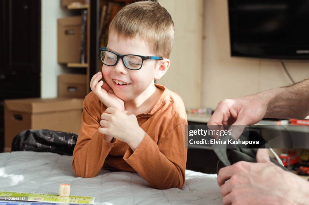 Portrait of a smiling boy 8 years old in glasses with a lotto bag in his hands. Child playing loto board game