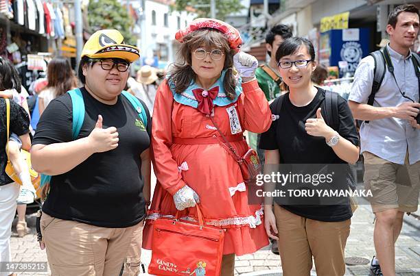 This photo taken on June 27, shows Yuzo Shiozawa a 60 year old Tokyoite dressed in a hand-made costume of cartoon heroine Candy posing with tourists...