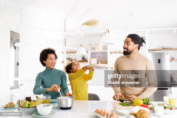 happy african american family having fun while baking pancakes in the kitchen. - throwing stock pictures, royalty-free photos & images