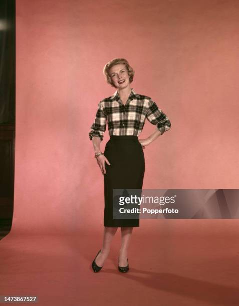 Posed studio portrait of a woman wearing a black and white plaid shirt and a slim black pencil skirt, London, 13th September 1958.