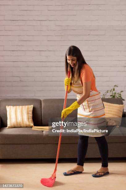 portrait of woman sweeping floor with a broom at home - broom stock pictures, royalty-free photos & images
