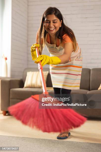 smiling woman sweeping floor with a broom at home - broom stock pictures, royalty-free photos & images