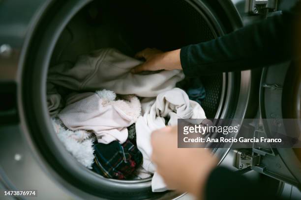 woman hands putting her dirty clothes in the washing machine in a laundromat - máquina de lavar roupa imagens e fotografias de stock