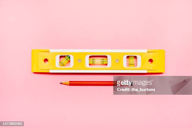 high angle view of yellow spirit level and pencil on pink background - spirit level stock pictures, royalty-free photos & images