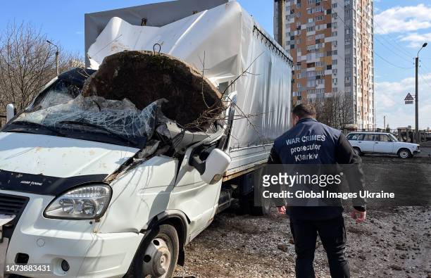War crimes prosecutor stands next to a van damaged by shelling of residential district on March 15, 2023 in Kharkiv, Ukraine. With a missile attack...