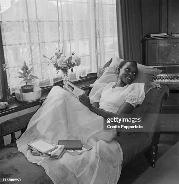 Ugandan actress Esther Makumbi seated on a chaise longue chair in the lounge of her rented house in Watford, England on 11th October 1945. Esther...