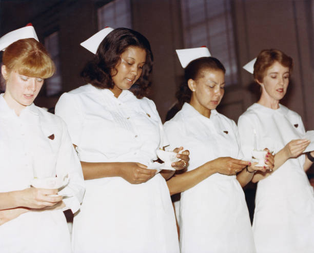 Nurses taking oath while holding candle at event.