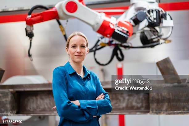 confident mature technician with arms crossed at factory - female factory stockfoto's en -beelden