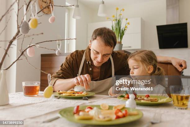 father and daughter eating pancakes for breakfast at home - easter bunny man stockfoto's en -beelden