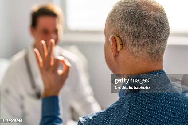 doctor and male patient with hearing aid - ear deafness stock pictures, royalty-free photos & images
