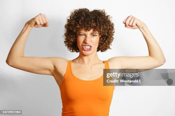 woman flexing muscles against white background - flexionar los músculos fotografías e imágenes de stock