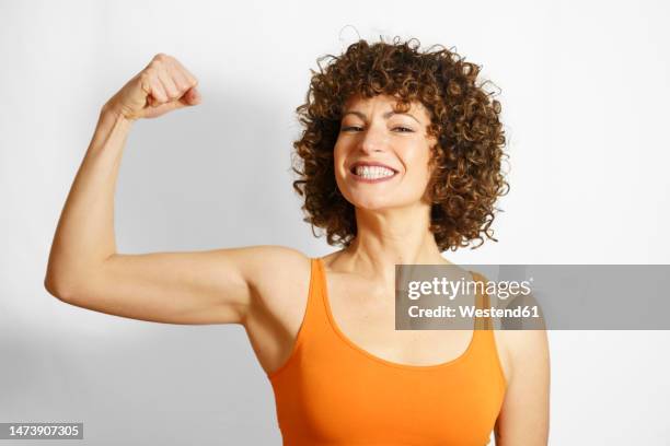 happy woman flexing muscles against white background - flexionar los músculos fotografías e imágenes de stock