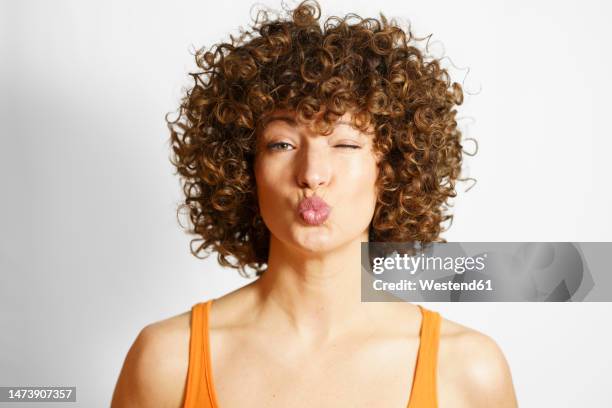 woman with curly hair puckering face against white background - puckering stock pictures, royalty-free photos & images