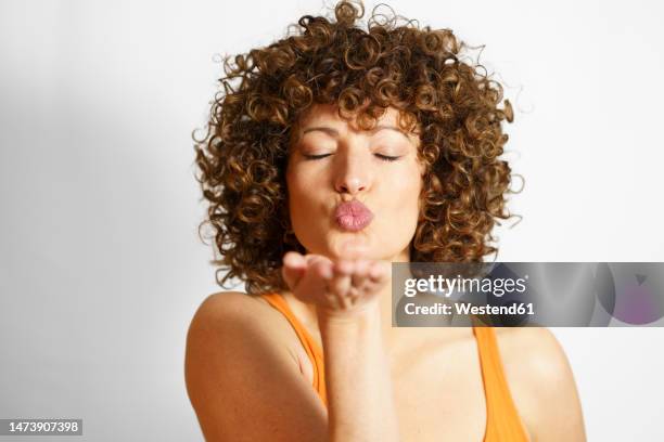 woman blowing kiss against white background - kussmund stock-fotos und bilder