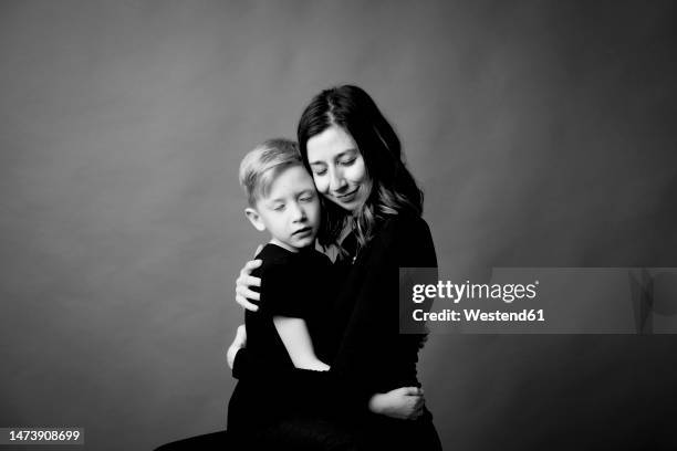 affectionate mother and son embracing with eyes closed - affectionate stock-fotos und bilder