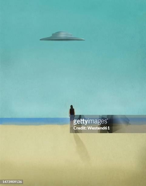person looking at flying saucer hovering over sandy beach - hovering stock illustrations