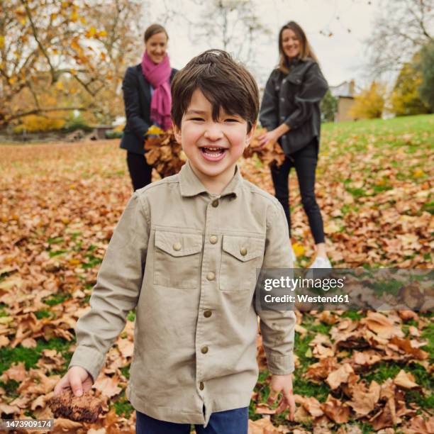 happy boy standing on autumn leaves at park - nephew stock pictures, royalty-free photos & images