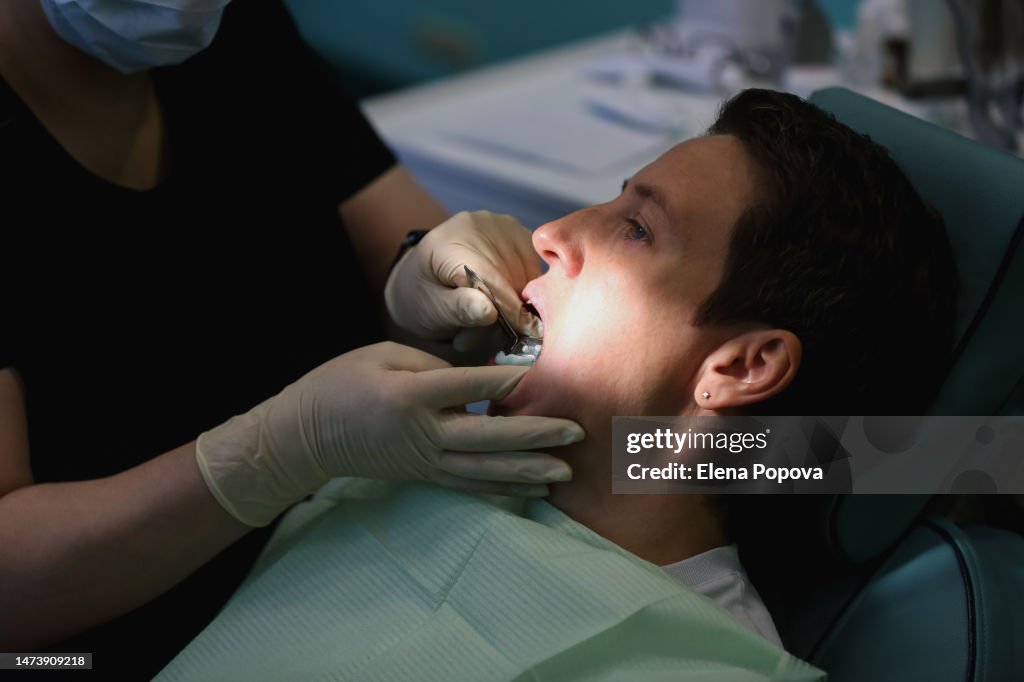 Female Orthodontist Working Carefully On Mid Adult Patient And Sculpting Dentures. Ambient Electric Light