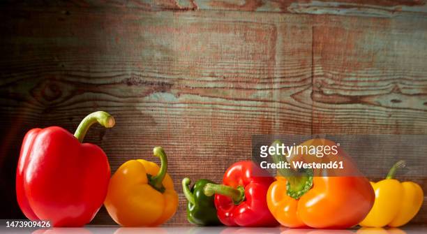 fresh bell peppers against wooden background - orange bell pepper fotografías e imágenes de stock
