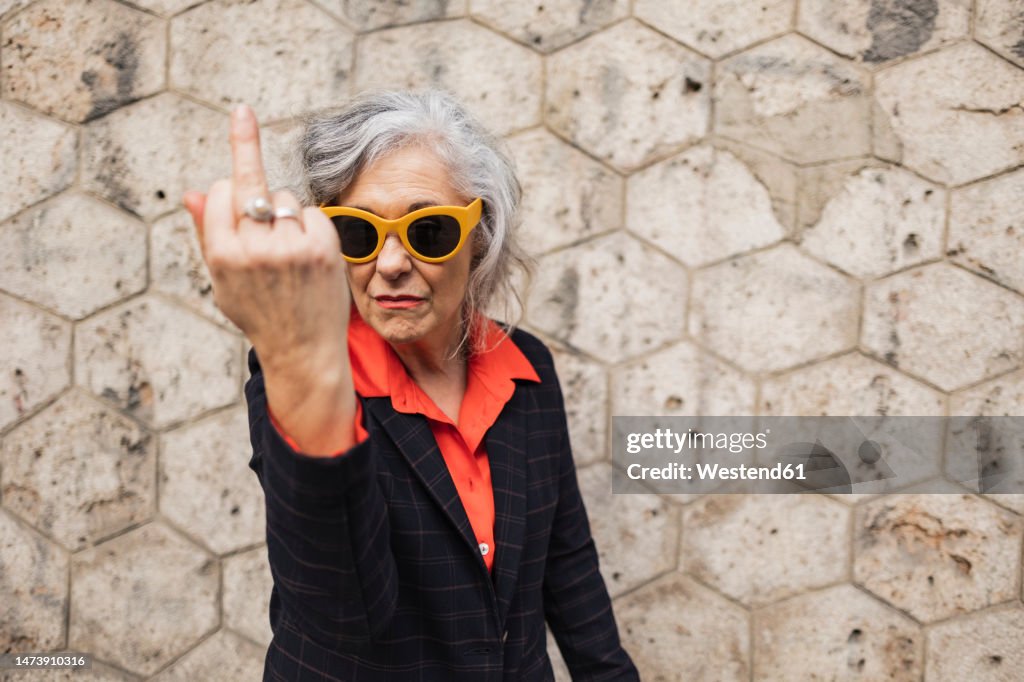 Mature businesswoman gesturing in front of wall
