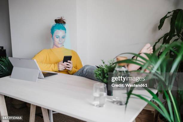 freelancer using smart phone sitting in home office - facial recognition technology stock pictures, royalty-free photos & images