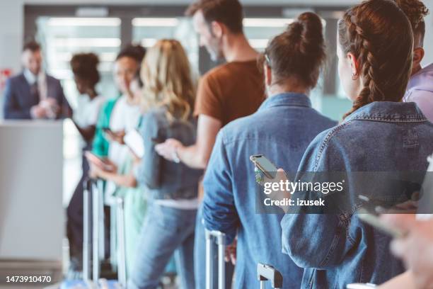 pasajeros con equipaje esperando en la fila del aeropuerto - hacer cola fotografías e imágenes de stock