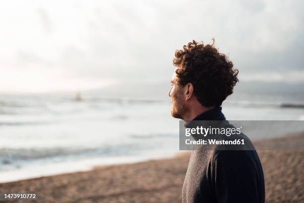 thoughtful mature man looking at sea from beach - roupa quente imagens e fotografias de stock