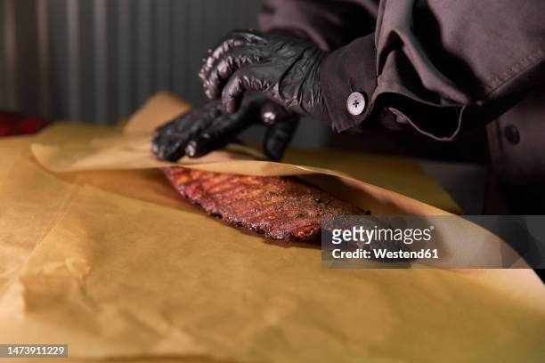 chef wrapping meat in butcher paper - butcher paper foto e immagini stock