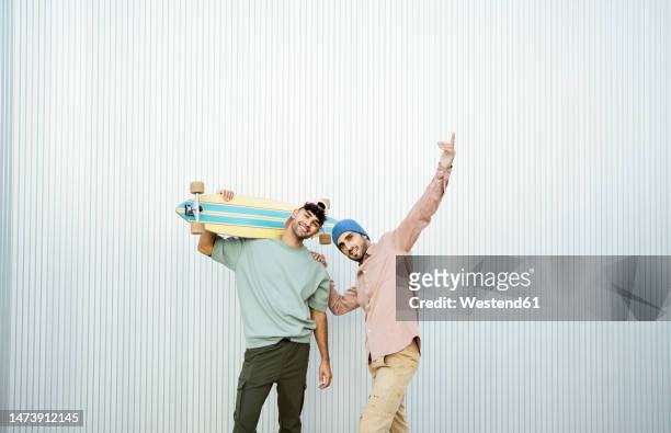 two men standing with longboard in front of white wall - longboard stock-fotos und bilder